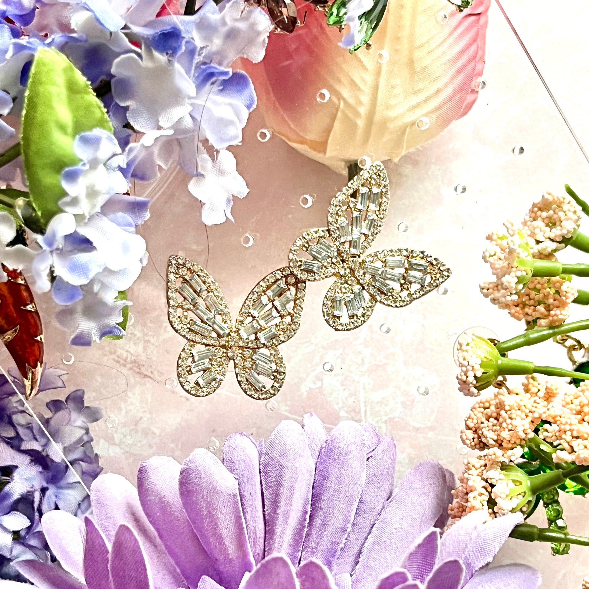 “pretty fly for a butterfly” butterfly earrings by statement earrings brand, Gumptious. Features silver butterflies with their wings outlined in rhinestones and then completely filled out in full with more rhinestones for a reflective look. 